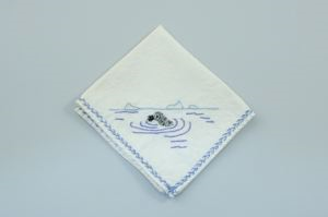 Image of Seal in ocean with ripples around it, one of a set of 4 embroidered napkins, each with different outdoor activity 